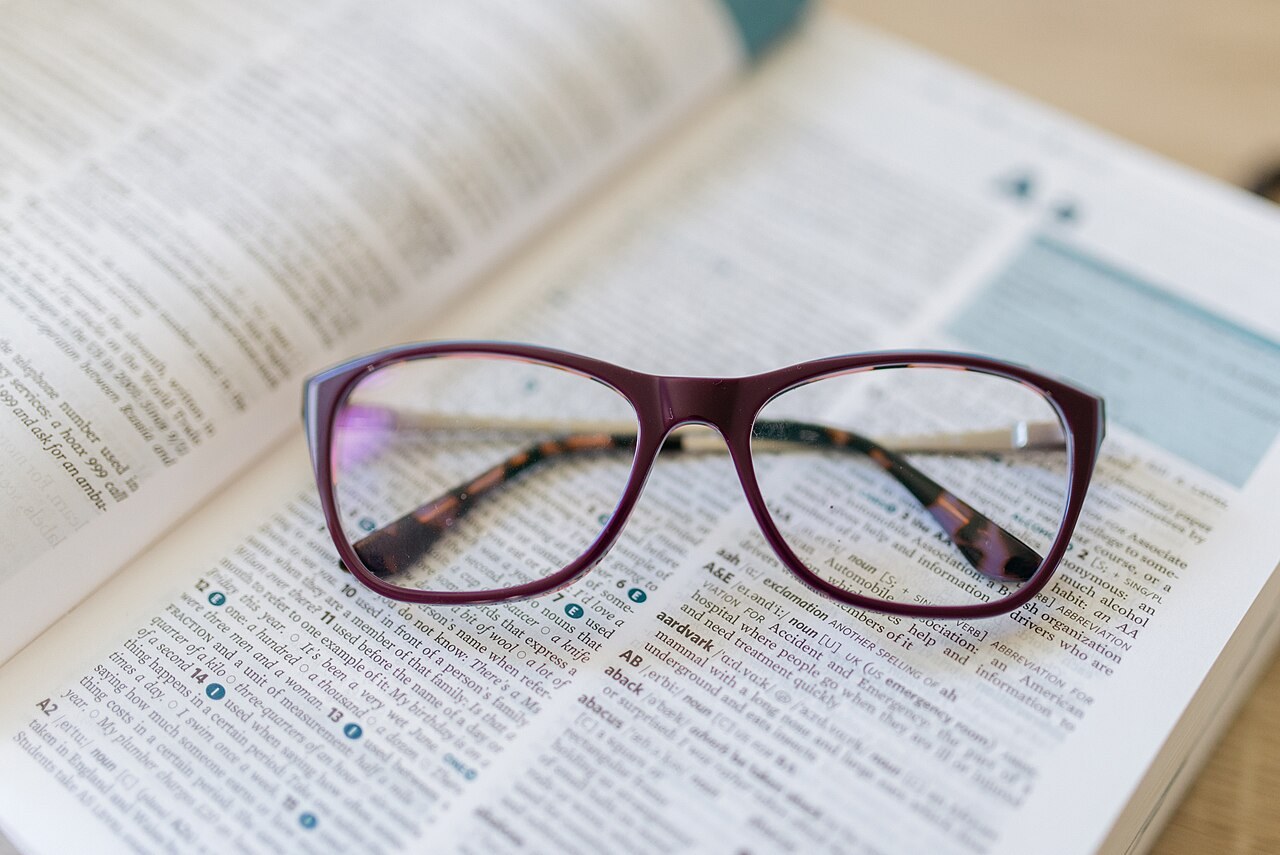 Reading glasses resting on an open reference book. Illustrative file photograph, not a copy of The Law of Cohesion.